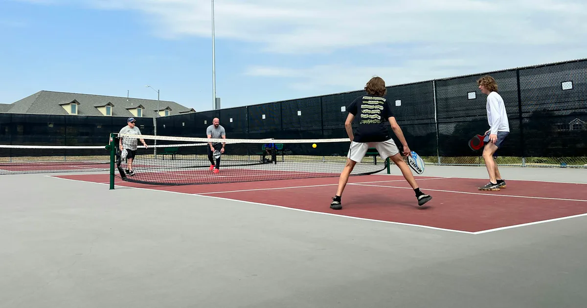 Four recreational players competing in an outdoor doubles pickleball match